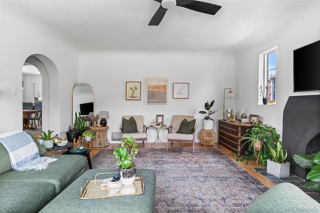 living area featuring arched walkways, wood finished floors, and ceiling fan