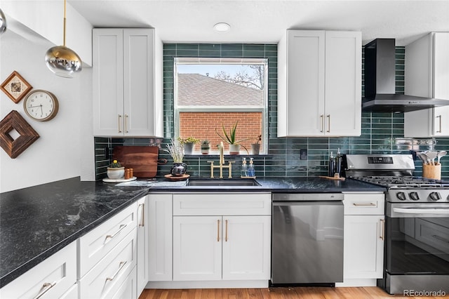 kitchen with tasteful backsplash, wall chimney exhaust hood, a sink, and appliances with stainless steel finishes