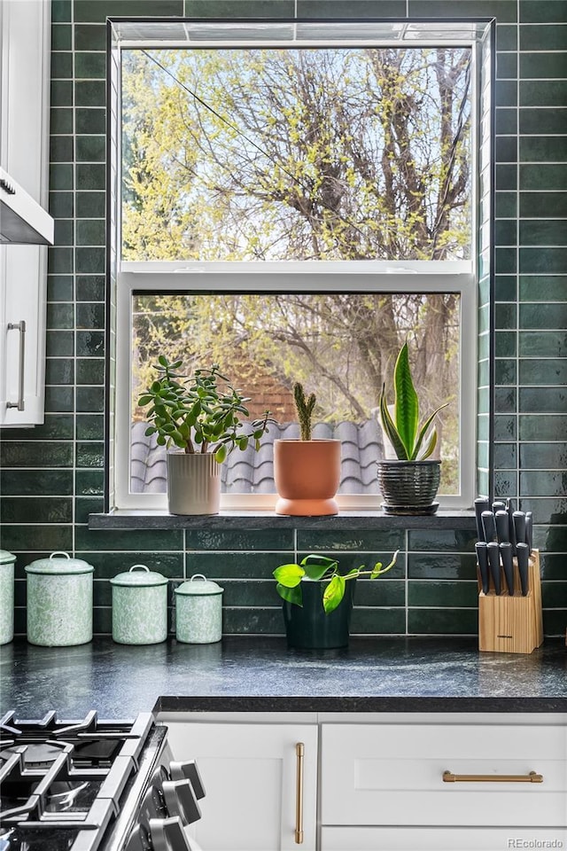 details featuring dark countertops, wall chimney exhaust hood, white cabinetry, and decorative backsplash