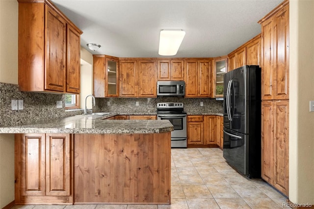 kitchen featuring tasteful backsplash, glass insert cabinets, a peninsula, stainless steel appliances, and a sink