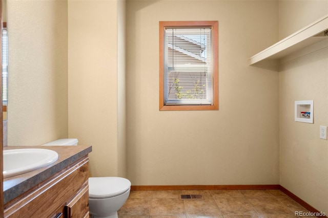 half bathroom with visible vents, toilet, vanity, and baseboards