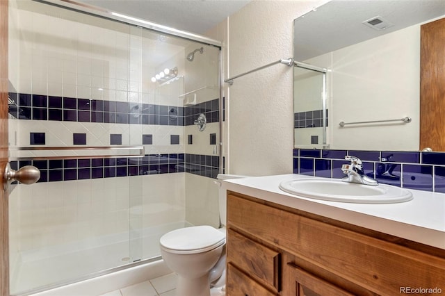 full bath with toilet, vanity, visible vents, and a textured wall