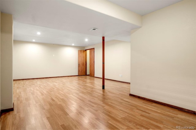 finished below grade area featuring light wood finished floors, visible vents, baseboards, and recessed lighting