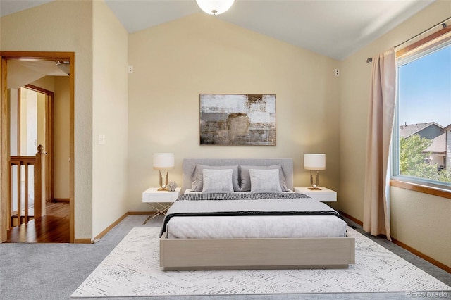 bedroom with vaulted ceiling, baseboards, and light colored carpet