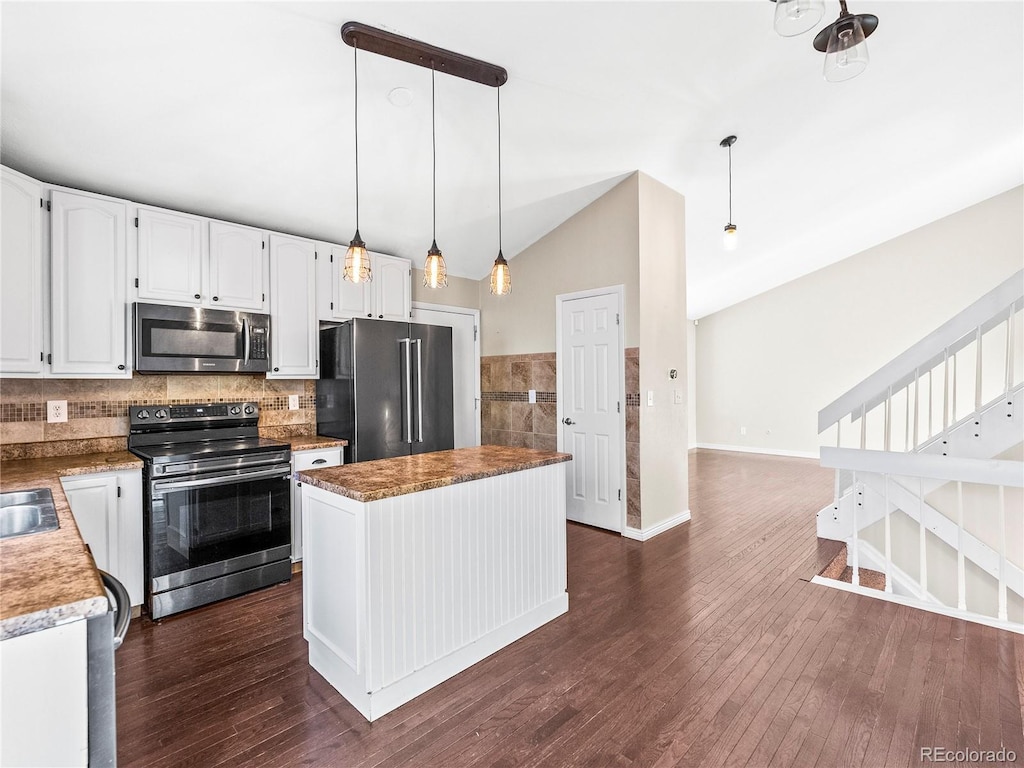 kitchen featuring lofted ceiling, a kitchen island, stainless steel appliances, and decorative light fixtures