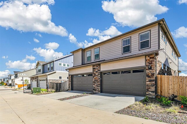 21761 E 7th Ave, Aurora, CO 80018 - townhome / multi-family property with an attached garage, stone siding, driveway, and fence
