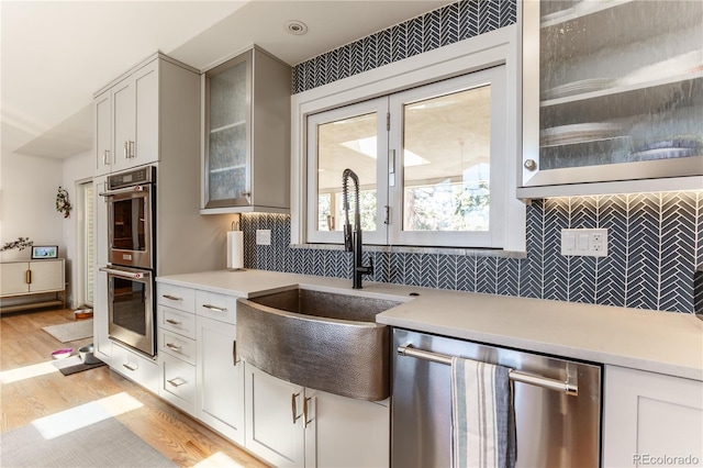 kitchen featuring light countertops, a sink, light wood-style floors, and appliances with stainless steel finishes
