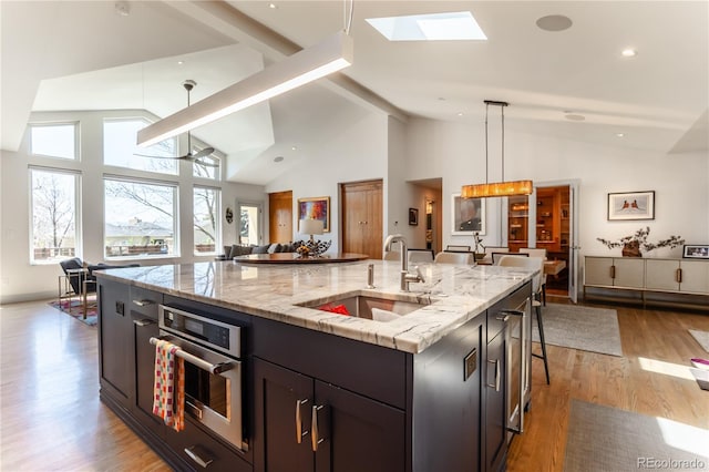 kitchen with oven, a large island, a sink, light wood-type flooring, and open floor plan