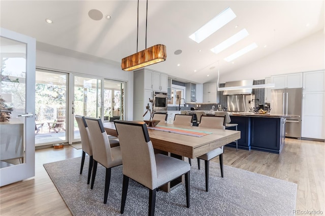 dining space with a skylight, high vaulted ceiling, light wood-style floors, and recessed lighting