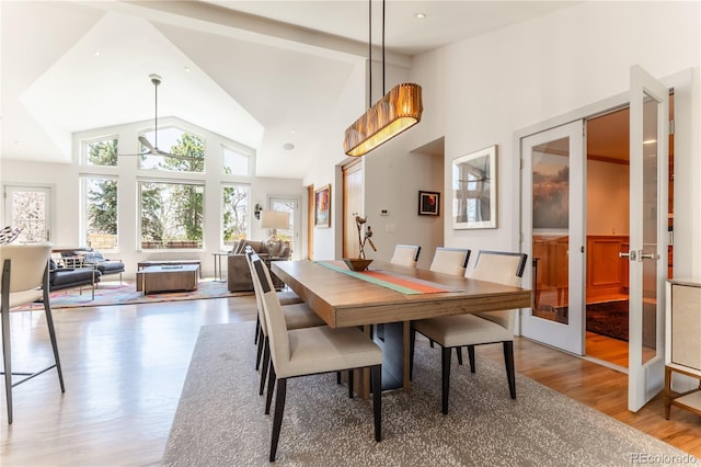 dining room with light wood-style flooring, french doors, and high vaulted ceiling