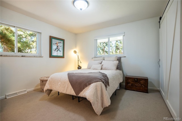 bedroom with light carpet, multiple windows, visible vents, and baseboards