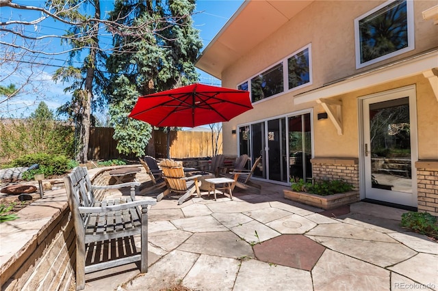 view of patio featuring an outdoor fire pit and fence