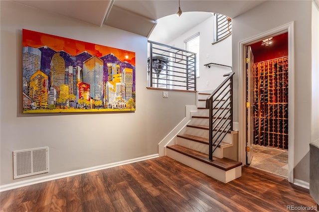 wine cellar featuring baseboards, wood finished floors, visible vents, and arched walkways