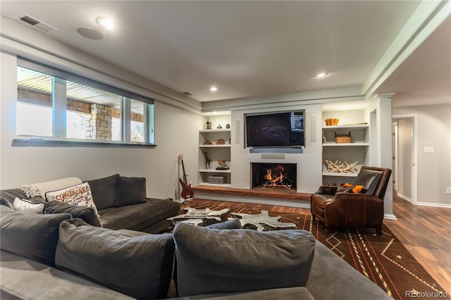 living area with recessed lighting, dark wood finished floors, visible vents, baseboards, and a lit fireplace