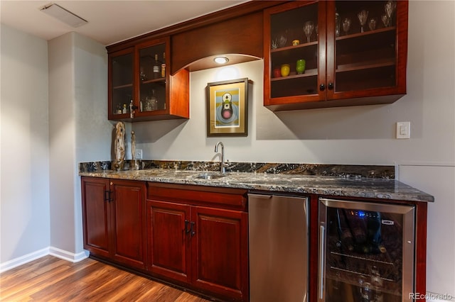 bar with wine cooler, wet bar, wood finished floors, a sink, and baseboards