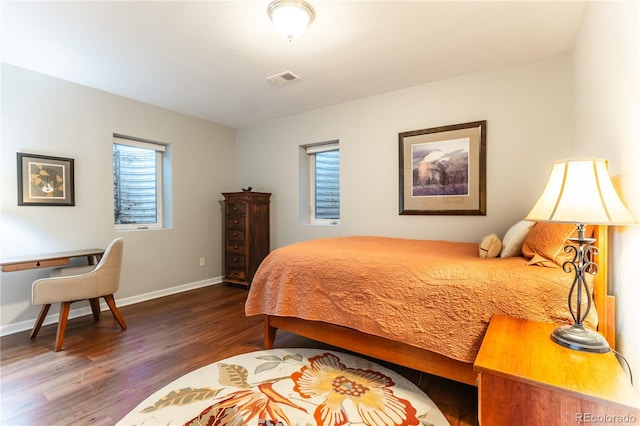 bedroom with baseboards, wood finished floors, and visible vents