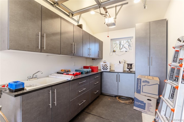 kitchen with dark countertops, a sink, and concrete floors