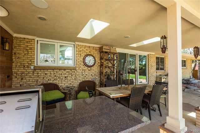 dining room with brick wall, ornamental molding, and a skylight