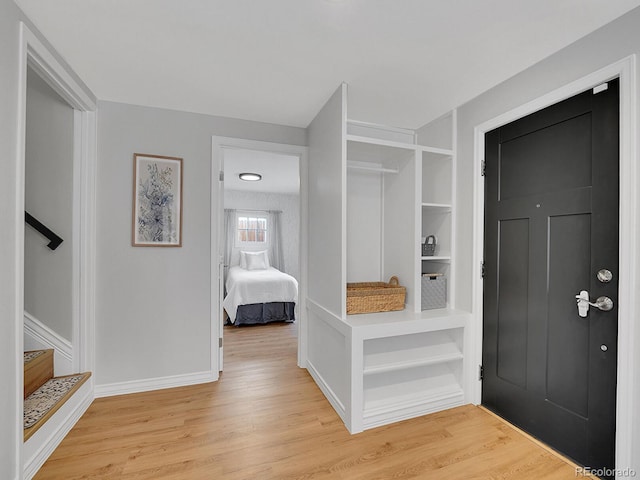 mudroom featuring light wood finished floors, built in shelves, and baseboards