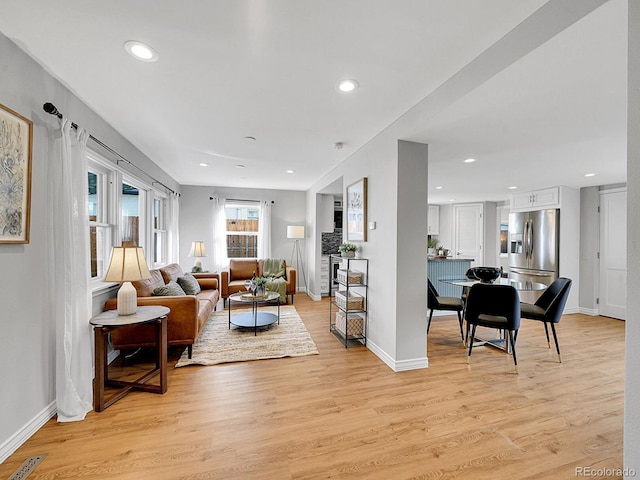 living room with baseboards, light wood finished floors, visible vents, and recessed lighting