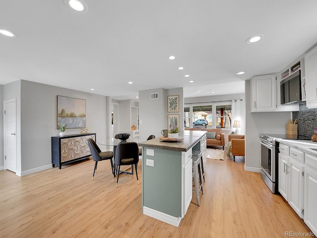 kitchen featuring light wood finished floors, visible vents, white cabinets, a kitchen island, and stainless steel appliances