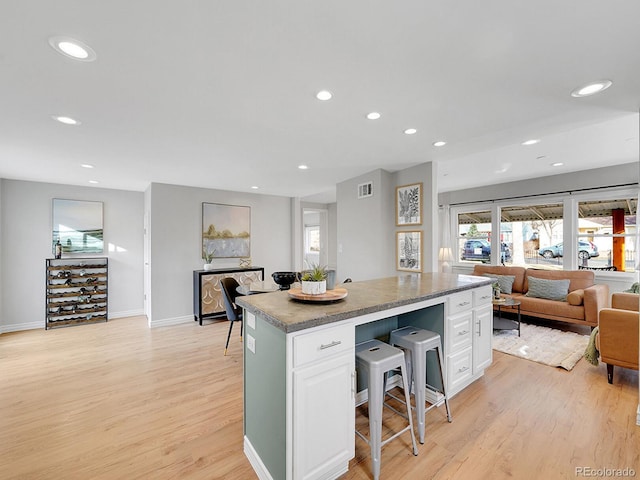 kitchen featuring white cabinets, light wood finished floors, open floor plan, and a center island