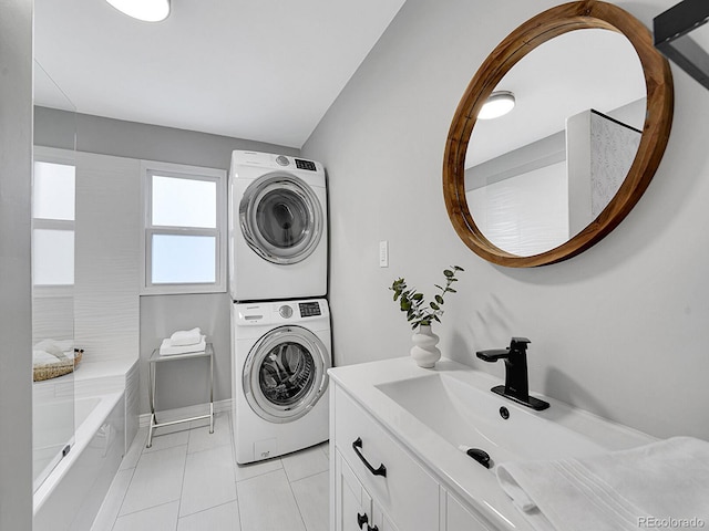 laundry area featuring a sink, laundry area, light tile patterned floors, and stacked washer / dryer