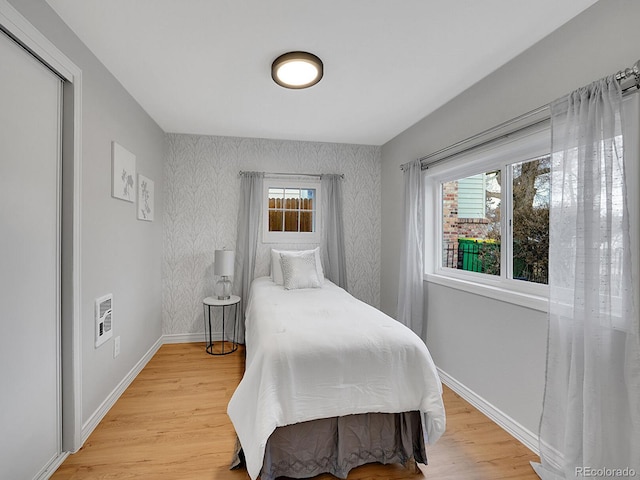 bedroom featuring multiple windows, light wood-type flooring, and baseboards