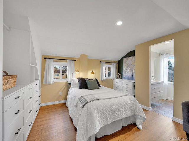 bedroom featuring lofted ceiling, multiple windows, and light wood-style flooring