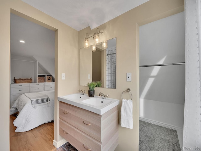 bathroom with double vanity, a sink, and wood finished floors