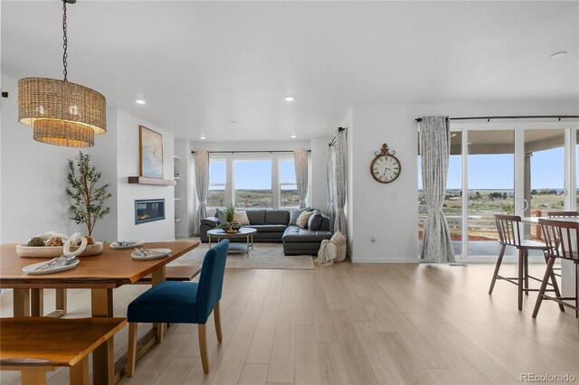 13446 Amber Sky St, Parker, CO 80134 - dining space featuring a glass covered fireplace, light wood-style flooring, baseboards, and recessed lighting
