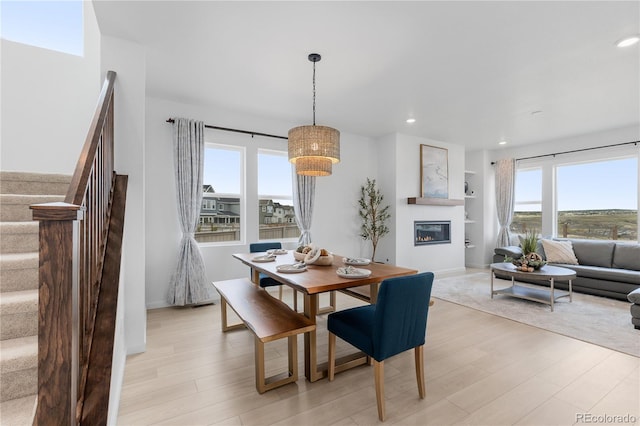 13446 Amber Sky St, Parker, CO 80134 - dining area with light wood-style floors, plenty of natural light, a glass covered fireplace, stairs, and recessed lighting