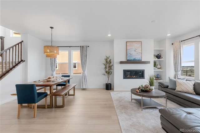 13446 Amber Sky St, Parker, CO 80134 - living area featuring stairway, light wood-style flooring, a glass covered fireplace, recessed lighting, and baseboards