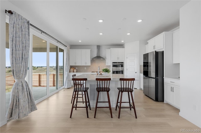 13446 Amber Sky St, Parker, CO 80134 - kitchen with stainless steel appliances, wall chimney exhaust hood, light countertops, light wood-style floors, and white cabinets