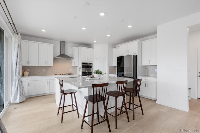 13446 Amber Sky St, Parker, CO 80134 - kitchen featuring wall chimney exhaust hood, a kitchen bar, appliances with stainless steel finishes, light wood-type flooring, and recessed lighting