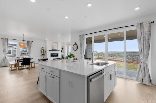 13446 Amber Sky St, Parker, CO 80134 - kitchen with stainless steel dishwasher, a sink, white cabinetry, light countertops, and an island with sink