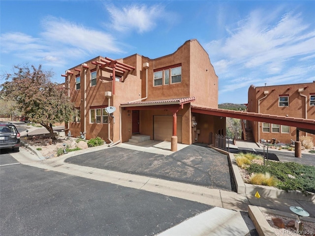 view of front facade with a garage, stucco siding, and asphalt driveway