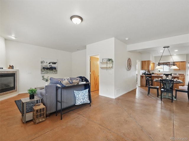 living area with baseboards, concrete floors, recessed lighting, and a glass covered fireplace