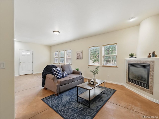 living area with a tile fireplace and baseboards
