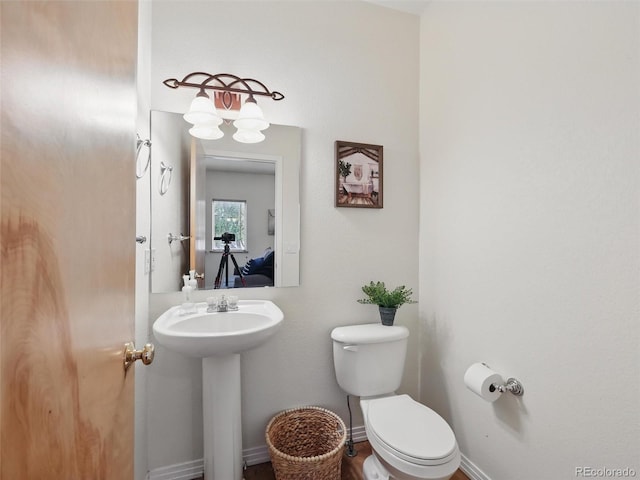 bathroom featuring toilet, baseboards, and a sink