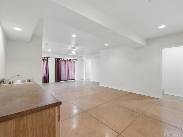 empty room featuring a sink, light tile patterned floors, baseboards, and recessed lighting
