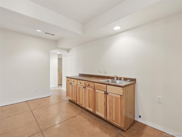 bar area with arched walkways, recessed lighting, a sink, and baseboards