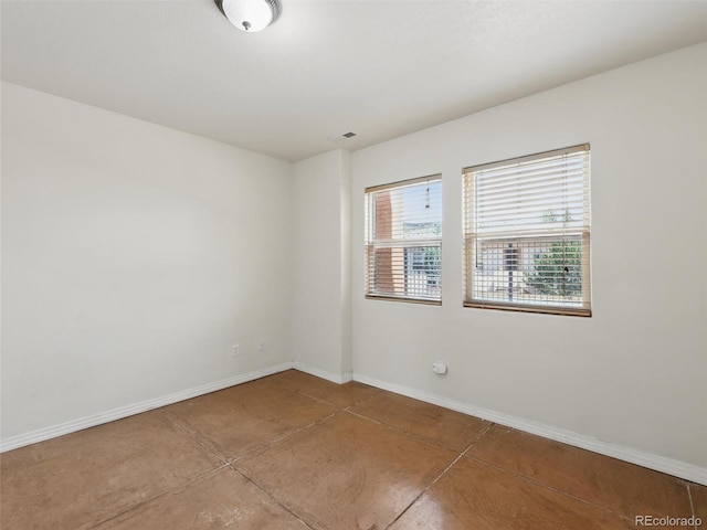 spare room with baseboards and concrete flooring