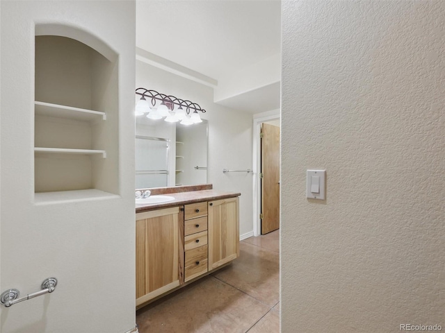 full bathroom featuring tile patterned floors, vanity, and a textured wall