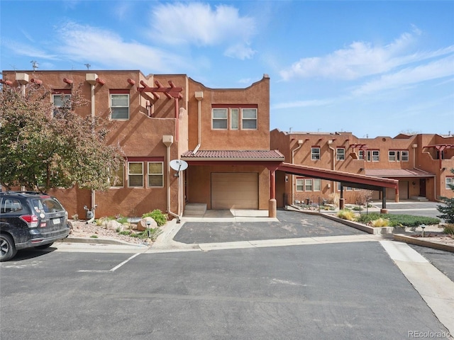 view of front of home featuring an attached garage, stucco siding, asphalt driveway, and a residential view