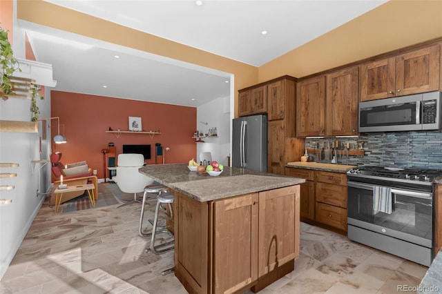 103 Trout Run Dr, Carbondale, CO 81623 - kitchen with appliances with stainless steel finishes, backsplash, a kitchen breakfast bar, brown cabinetry, and a kitchen island