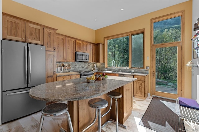 103 Trout Run Dr, Carbondale, CO 81623 - kitchen featuring appliances with stainless steel finishes, tasteful backsplash, a kitchen island, a breakfast bar, and dark stone counters