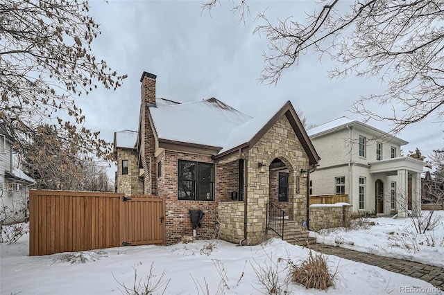 view of front of house featuring stone siding, brick siding, and a chimney