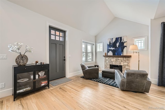 entryway featuring vaulted ceiling, a healthy amount of sunlight, a fireplace, and wood finished floors