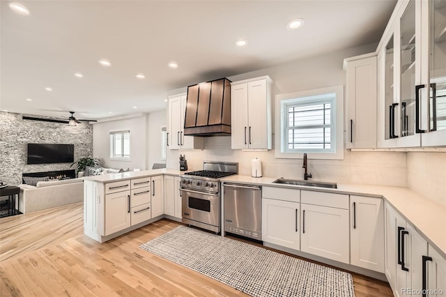 kitchen with light countertops, appliances with stainless steel finishes, open floor plan, white cabinets, and a sink